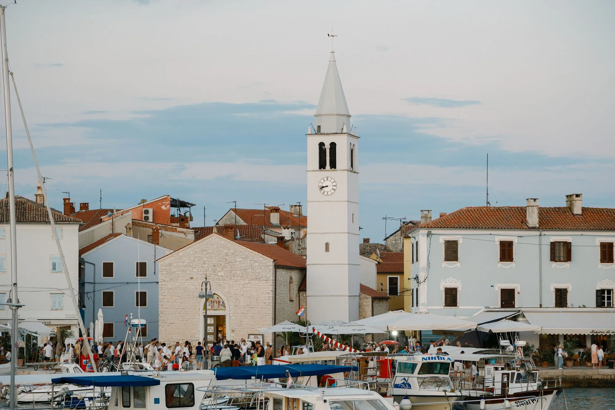Večer u istarskoj luci — Fažana s crkvenim tornjem, barkama i gostima na rivi